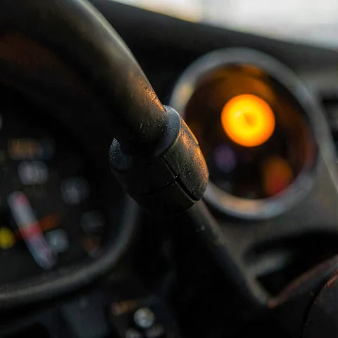 Macro of an indicator stalk on a steering column, an amber indicator light glowing behind it