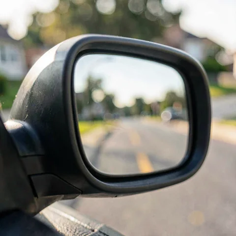 Macro of a car side mirror housing reflecting a blurred suburban street