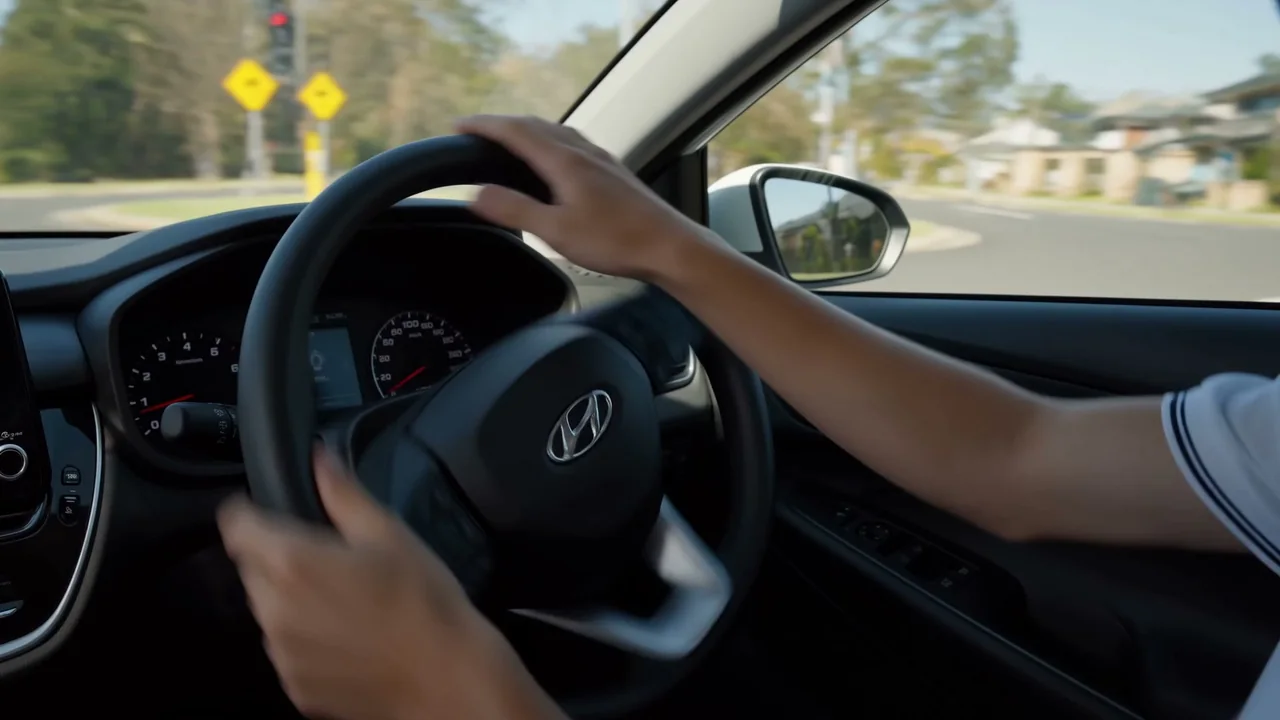 A learner’s hands set at nine and three on the wheel, approaching a give-way intersection
